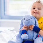 a child sitting in a hospital bed holding a stuffed animal