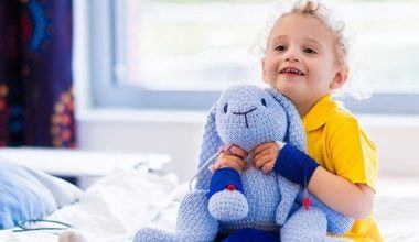 a child sitting in a hospital bed holding a stuffed animal