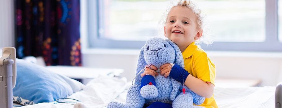 a child sitting in a hospital bed holding a stuffed animal