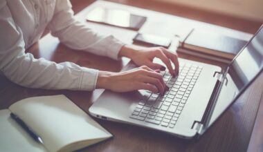 Person sitting at a desk typing on a laptop.
