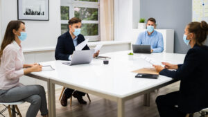 Employees with masks sitting around a desk.