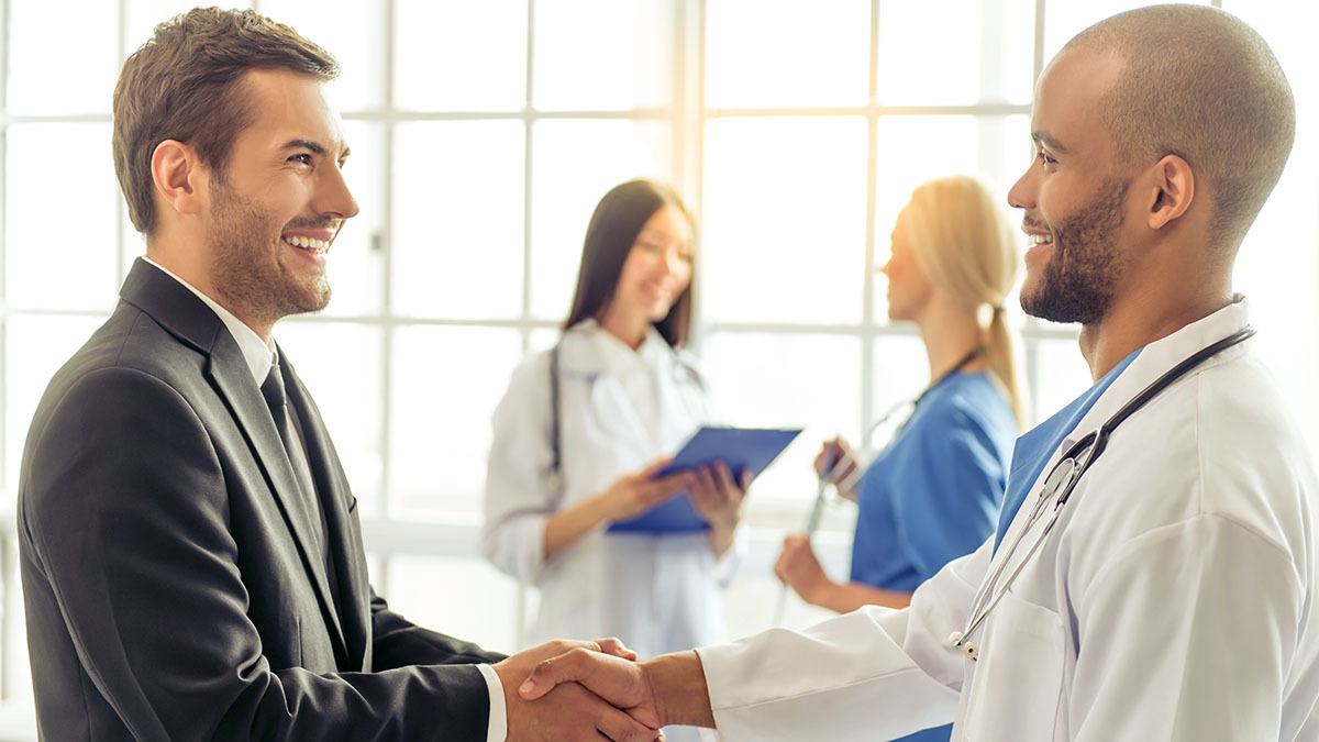 A doctor and a man in a suit shake hands