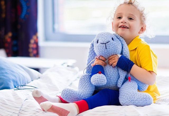child in hospital holding stuffed animal