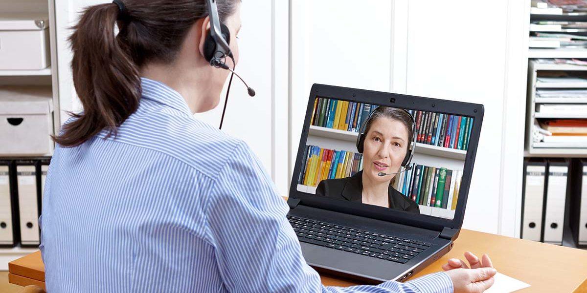 Woman with headset has video call on her laptop