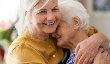 Smiling woman hugging her elderly mother
