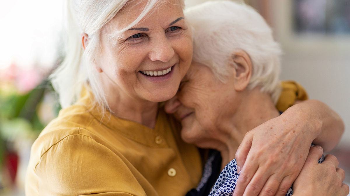 Smiling woman hugging her elderly mother