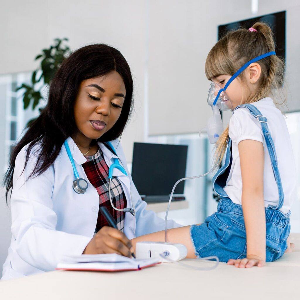 Pediatric doctor taking notes while a child breaths through a mask.