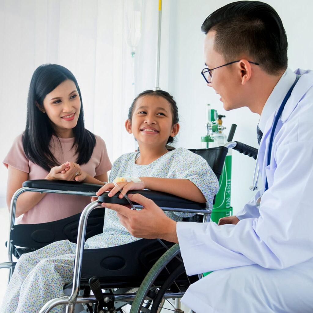 Pediatric doctor speaking to a mother and her child that is in a wheelchair.