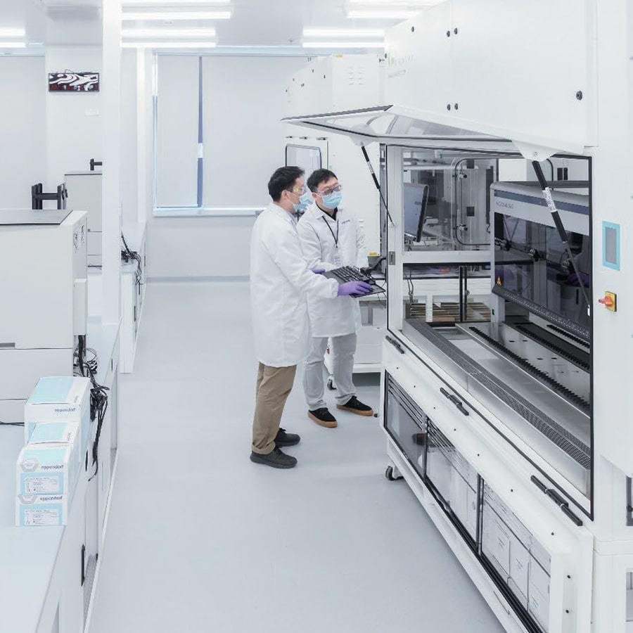 Vaccine Sciences lab with two technicians reading a computer monitor.