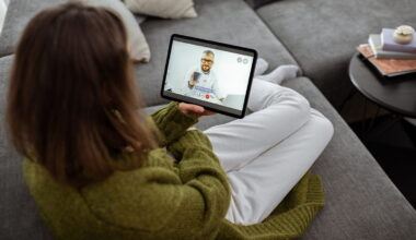 Patient sitting on couch, talking with telehealth doctor on tablet
