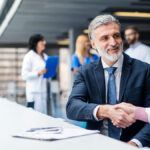 Man with a beard in a suit shakes hands with a female doctor