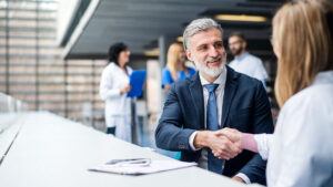 Man with a beard in a suit shakes hands with a female doctor
