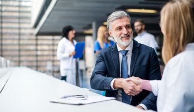Man with a beard in a suit shakes hands with a female doctor