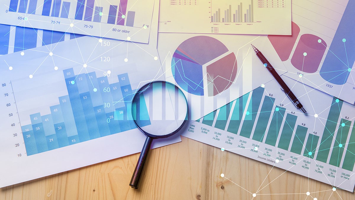 Various charts and graphs and a magnifying glass laying on a table