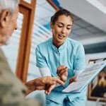Patient and nurse having discussion with doctor taking notes.