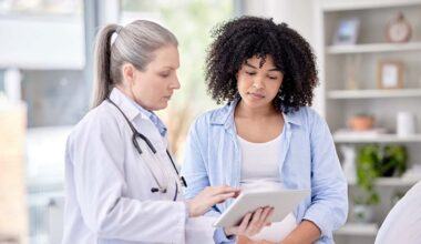 Doctor speaking to a patient while holding a tablet.