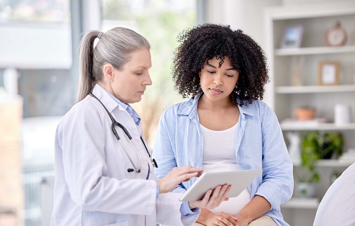 Doctor speaking to a patient while holding a tablet.