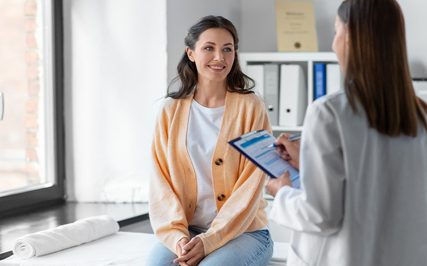 Female patient speaking to a female nurse who is taking notes.