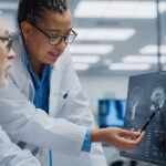 Biomarker-driven CNS trials lab with two researchers looking at a monitor with a cat scan result