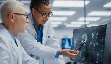 Biomarker-driven CNS trials lab with two researchers looking at a monitor with a cat scan result