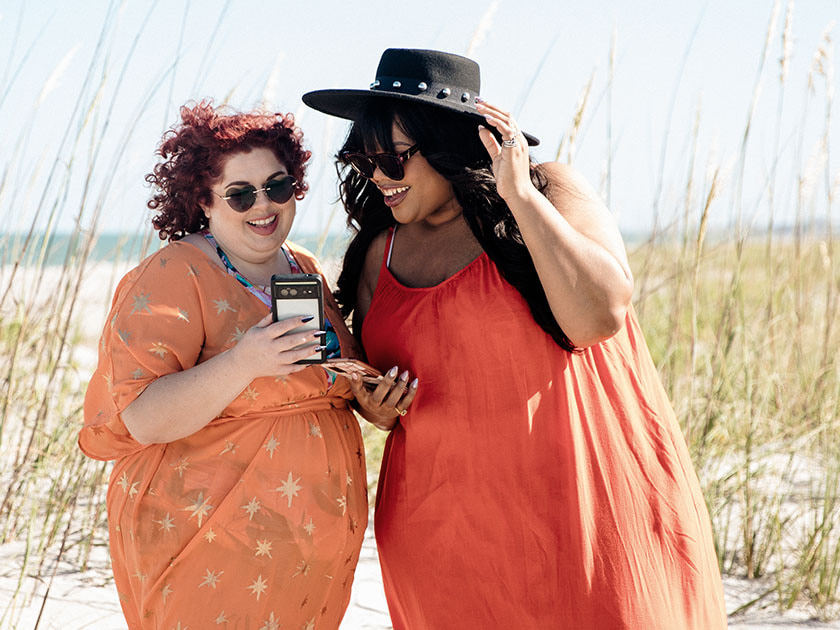 Two overweight females on a beach checking their metabolic app as part of a chronic disease clinical trial